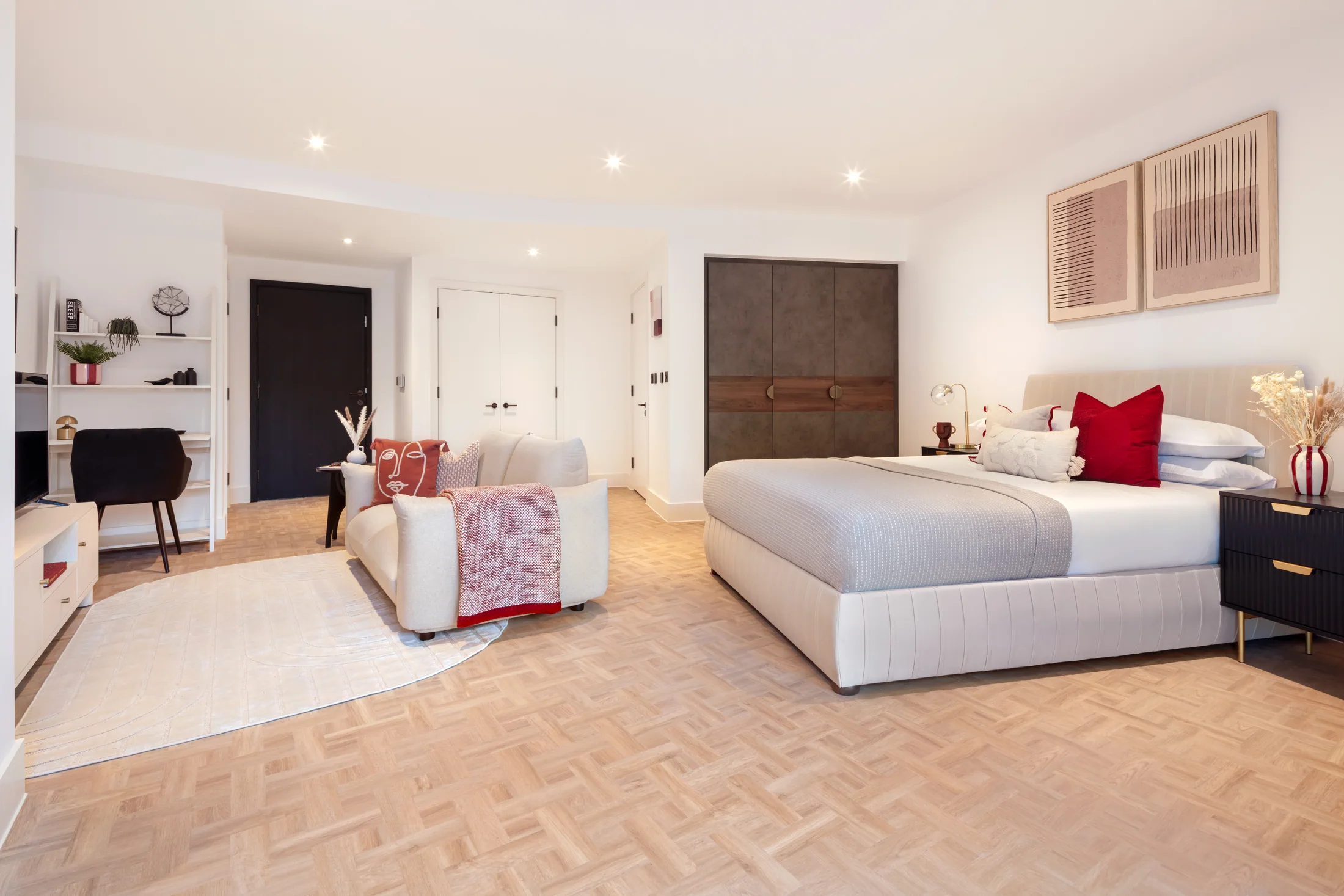 Show home looking across the Clapham studio's dressed bed, lounge chairs and fitted furniture