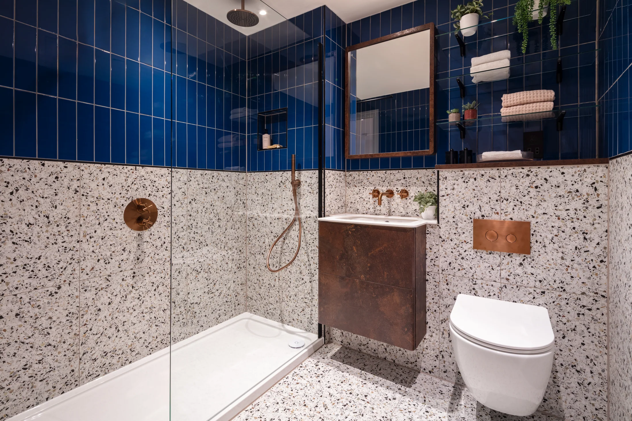 One Clapham existing bathroom featuring vivid blue wall tiles and patterned terrazzo-effect finishes