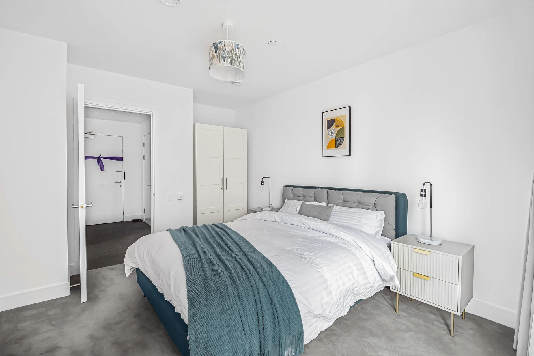 Second furnished bedroom with white bed linen, blue-green throw, bedside tables and decorative artwork