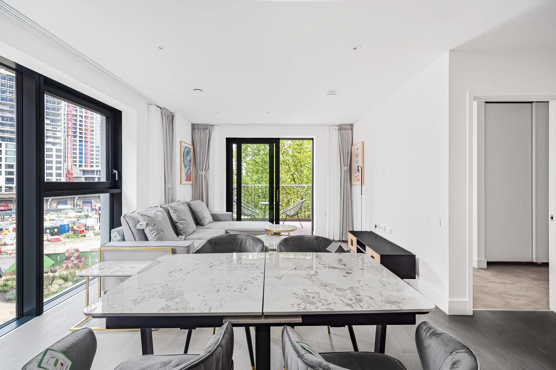 View from the dining table towards a softly furnished living space and full-height windows