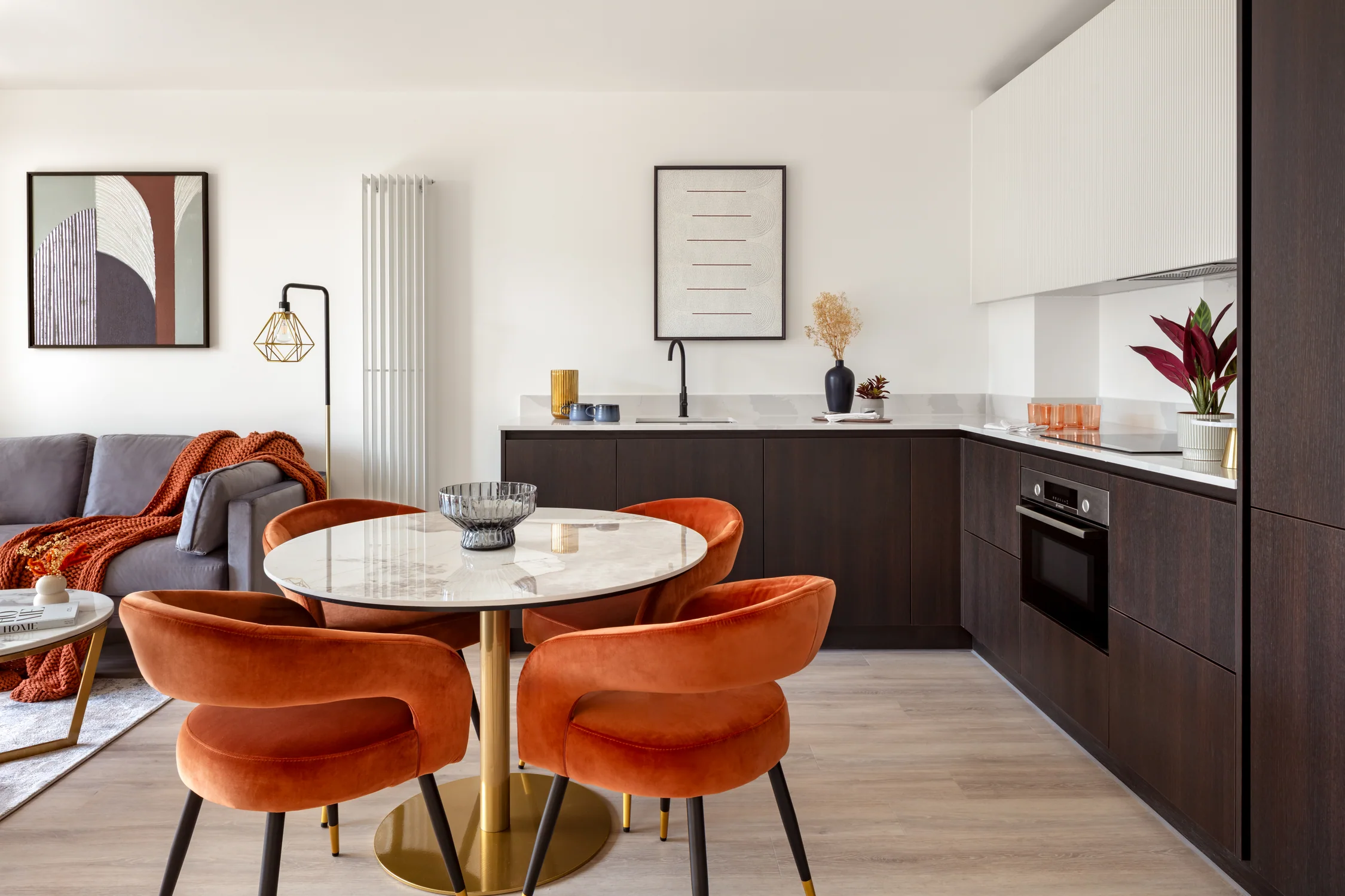 Round dining table with four copper-orange chairs beside the kitchen